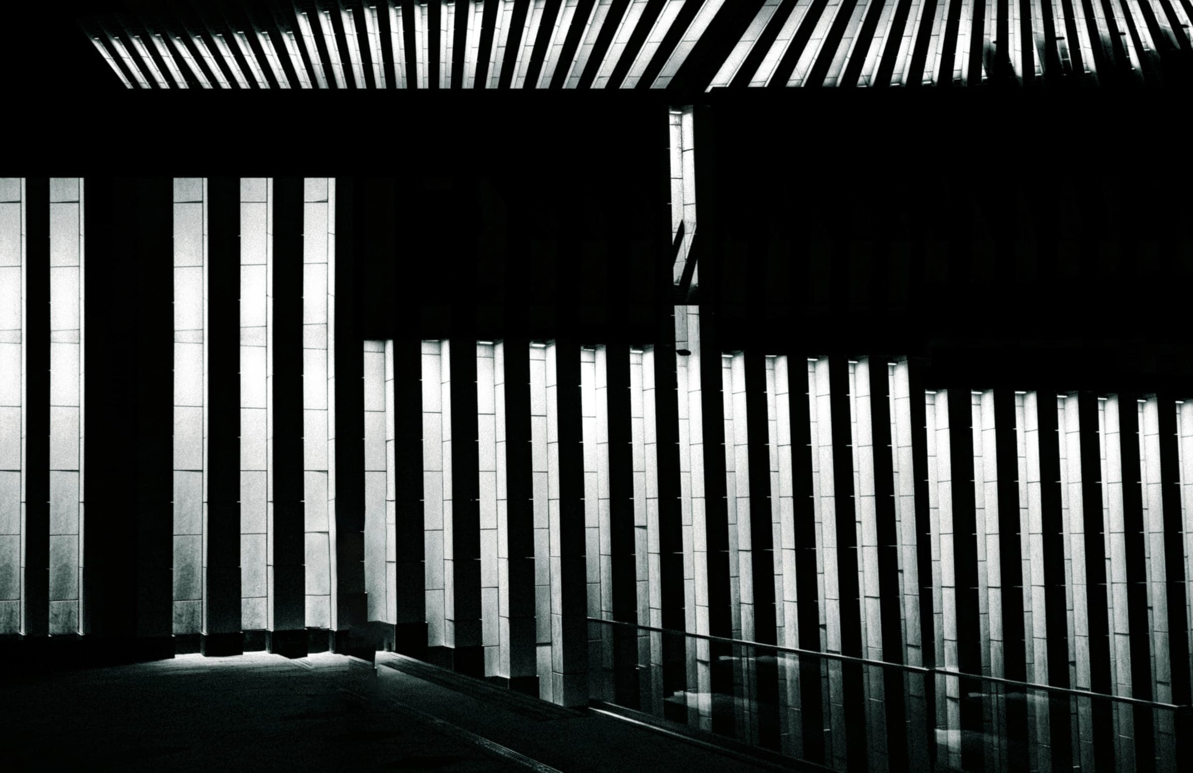 Light falling through vertical slats into a dark interior under a slatted ceiling.